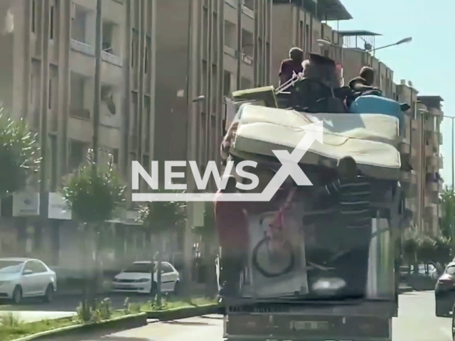 Several people travel dangerously by sitting on the furniture packed on a lorry or grabbing the ropes used to keep the furniture in place in Diyarbakir, Turkey, Saturday, Aug. 6, 2022. The van driver was fined for 'putting passengers on the load and endangering traffic safety'. Note: Photo is a screenshot from the video (Newsflash)