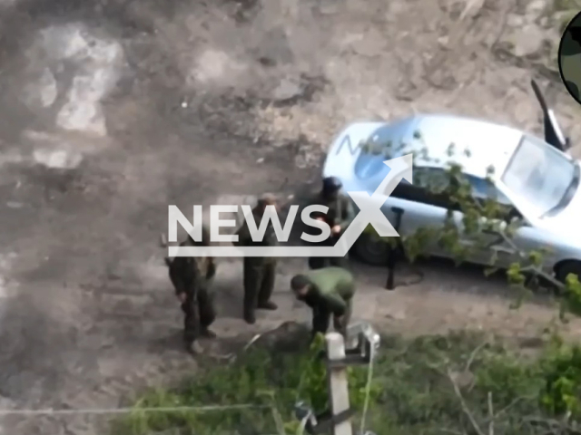 Russian soldiers stand near car with Z letter on it in a field area in Donetsk region, Ukraine in undated photo. Unit K2 of the 54th separate mechanized brigade dropped bombs on Russian soldiers. Note: Picture is a screenshot from a video (@K2.54OMBr/Newsflash)