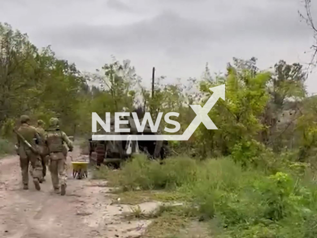 Ukrainian soldiers go down the road near Russian abandoned military vehicle near Sviatohirsk, Ukraine in undated photo. Guards of the State Border Service showed Russian abandoned positions in Donetsk region. Note: This picture is a screenshot from the video (@dpsu.gov.ua/Newsflash).