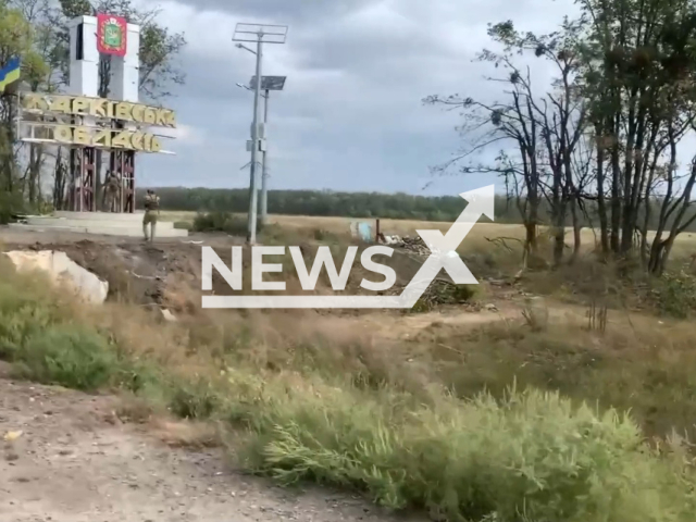 Ukrainian soldier stands near sign of Kharkiv region and Ukrainian flag in a field area in Ukraine in undated photo. Soldiers of the Airborne Assault Troops of the Armed Forces of Ukraine showed Russian abandoned military equipment in liberated Izyum. Note: Picture is a screenshot from a video (	
@www.dshv.mil.gov.ua/Newsflash)