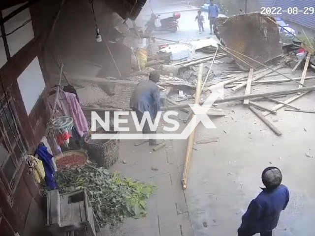 People gather around the boulder that smashed a house in Zhaotong, Yunnan in China on Monday, Aug. 29, 2022. The family reportedly said that both the grandmother and the kitten are safe. Note: Picture is a screenshot from a video (820650894/AsiaWire)