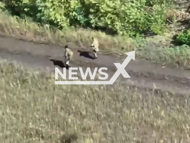 Russian soldiers go down the road in a forest area  in Ukraine in undated photo. Fighters of the separate brigade of Territorial Defense of the city of Dnipro shot at Russian military personnel with help of UAVs (Unmanned aerial vehicle). Note: This picture is a screenshot from the video (@BrTODnipro/Newsflash).