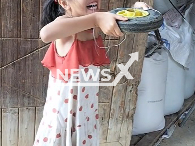 An eight-year-old girl uses a tire to pull her tooth in Fuyang, China, undated. She started to cry once the tooth fell off. Note: Picture is a screenshot from a video (338134567/AsiaWire)