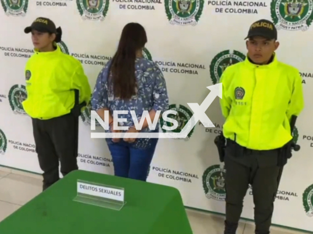 Picture shows the unidentified woman, 41, (middle) with two police officers during her arrest, in Rionegro, Colombia, on Friday, Sept. 23, 2022. She forced her 13-year-old stepson to have sex with her pet as punishment for bad behaviour.  Note: This picture is a screenshot from the video.  (@PoliciaBmanga/Newsflash)