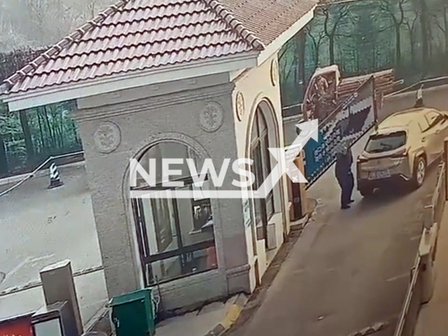 Security guard rushes to lift the gate that was about to hit the car in Yichang, China, on 27th February 2022. Note: Picture is a screenshot from a video (1291164905/AsiaWire)