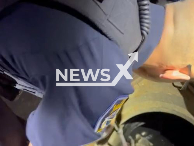 Police officers rescue a raccoon stuck in a catch basin in Yarmouth, Maine, the USA on Tuesday, Oct. 4, 2022. Note: Photo is a screenshot from a video.(Yarmouth Maine Police Department/Newsflash)