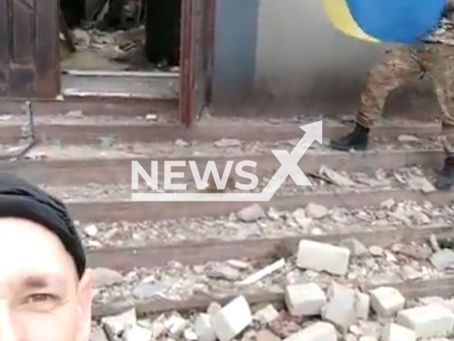 Ukrainian fighters hold Ukrainian flag near entrance of destroyed building in the village of Velyka Oleksandrivka, Kherson region, Ukraine in undated photo. Ukrainian police returned to Kherson region and raised the Ukrainian flag over the building of the police department in liberated village. Note: Photo is a screenshot from a video.(@khersonpolice.official/Newsflash)