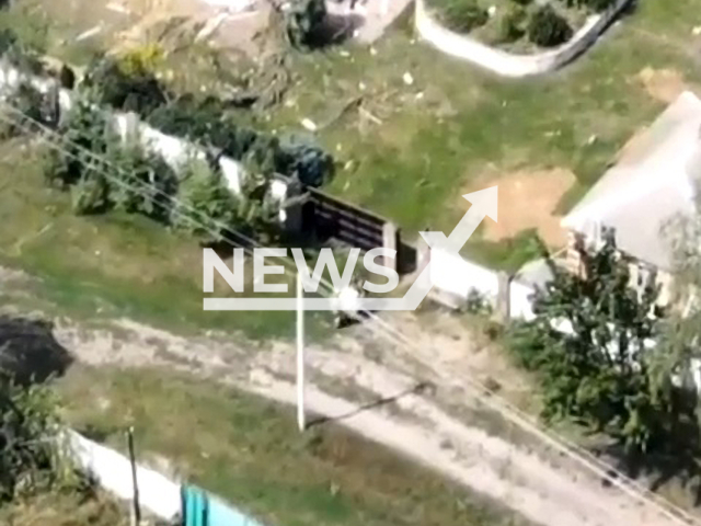 Two Russian soldiers carry washing machine in a residential area of Ukraine in undated photo. Ukrainian drone filmed Russian soldiers stealing washing machine from destroyed house and pulling it to their military truck with Z letter on it. Note: Picture is a screenshot from a video (@AFUStratCom/Newsflash)