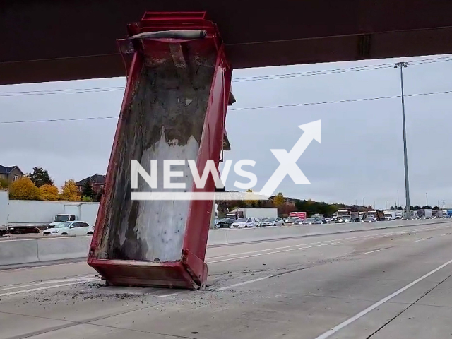 The dump truck box wedged between the highway and overpass in Ontario, Canada in undated video. Note: Picture is screenshot from a video (@OPP_HSD/Newsflash)