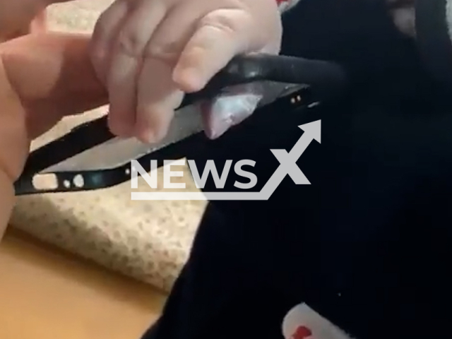 A member of the Kocaeli Fire Brigade cuts a phone case to free a baby's finger from it in Kocaeli, Turkey, in an undated video. Goktug Aydin Demir, the five-months-old baby got his finger stuck in the phone case.Note: Picture is screenshot from a video.(@kocaelibld/Newsflash)