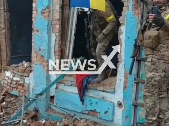 Ukrainian soldier makes photo with Ukrainian flag on destroyed building in Nevske settlement, Luhansk Region, Ukraine, Wednesday, Oct.26, 2022. Fighters of the Special Operations Forces of the Armed Forces of Ukraine raised Ukrainian flag in liberated village. Note: Photo is a screenshot from the video (@8regimentUkraine/Newsflash)