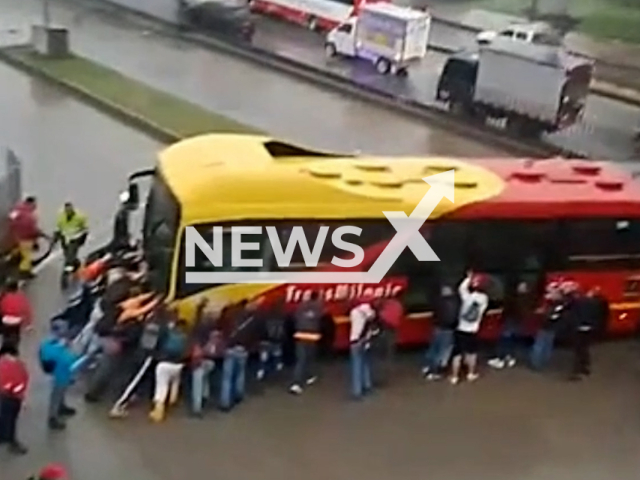 Passengers help push the bus in Bogota, Colombia, undated. The reasons for the buss failure are unknown. Note: Picture is screenshot from a video (@crisbus103/Newsflash).