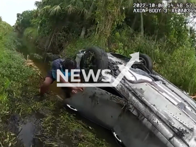 Deputy rescue three trapped in an overturned vehicle inside a canal in Indian River County, Florida, USA. Note: Picture is screenshot from a video. (Indian River County Sheriff's Office/Newsflash)