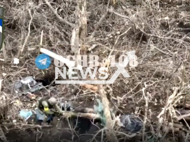 Ukrainian soldier shoots his gun into dugout with Russian soldiers in Ukraine in undated photo. Servicemen of the 108th Separate Mountain Assault Battalion of the 10th Mountain Assault Brigade cleared positions of Russian army. Note: Picture is a screenshot from a video (@108oghb/Newsflash)