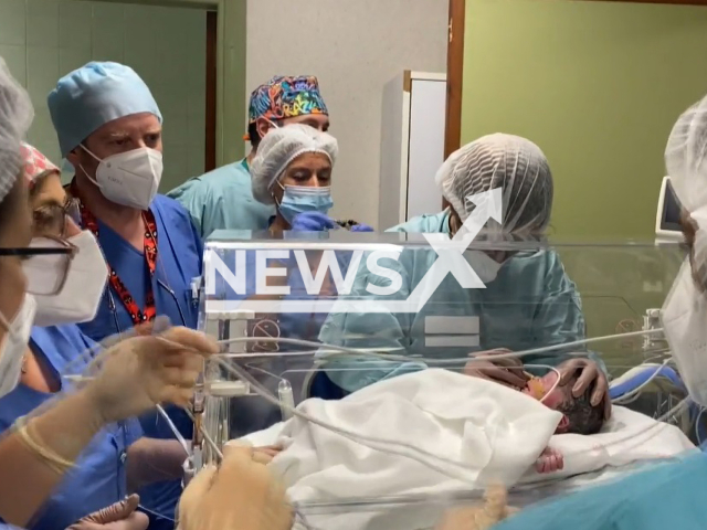 A member of the  medical staff   performs a   procedure on the baby in  Malaga, Spain, undated. 
A team of over 50 doctors  operated on a 36-week foetus  inside the mother's uterus in a pioneering case. Note: Photo is a screenshot from a video. (Newsflash)