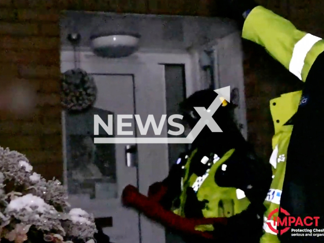 A police officer enters a residence to arrest suspects believed to have been smuggling drugs in Cheshire, England on Wednesday, Dec. 14, 2022.  The arrests came after a six-month-long investigation carried out by the Cheshire and the Merseyside police departments. Note: The picture is a screenshot from a video (Cheshire Police/Newsflash).