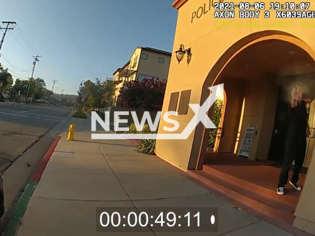 The suspect Matthew-Tuan Anh Tran, 22 points a gun at the police officers in front of the La Habra Police Station in California, USA on Friday, Aug. 6, 2021. The suspect was shot by the police officers and later pronounced dead by the paramedics. Note: The picture is a screenshot from the video. (OrangeCountyDA/Newsflash)