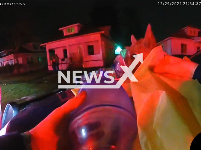 State troopers providing oxygen to a small dog after firefighters discovered it passed outside a burning house in Michigan, USA, undated. After giving the dog oxygen for approximately 15 minutes, Delilah regained consciousness and began breathing normally on its own. Note: The picture is a screenshot from the video. (@mspbayregion/Newsflash)