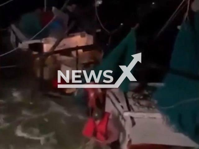 This photo shows two people narrowly escape being pulled down by their fishing boat as it sank in the freezing cold waters off North Carolina, USA, undated.Note: This picture is a screenshot from the video. (Go Coast Guard/Newsflash)