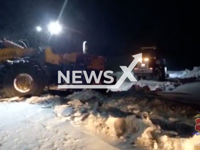 Picture shows two excavators, in Leninsk-Kuznetsky, Russia, in undated footage. Traffic police officers helped a tractor driver who had driven into a ditch. Note: Photo is screenshot from a video. (Kuzbass Police/Newsflash)