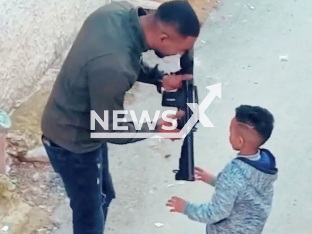 A man gives a gun to a child who fires it in Nablus, Palestine, undated. Israel Defense forces shared the video on their social media. Note: Picture is screenshot from a video. (@IDF/Newsflash)