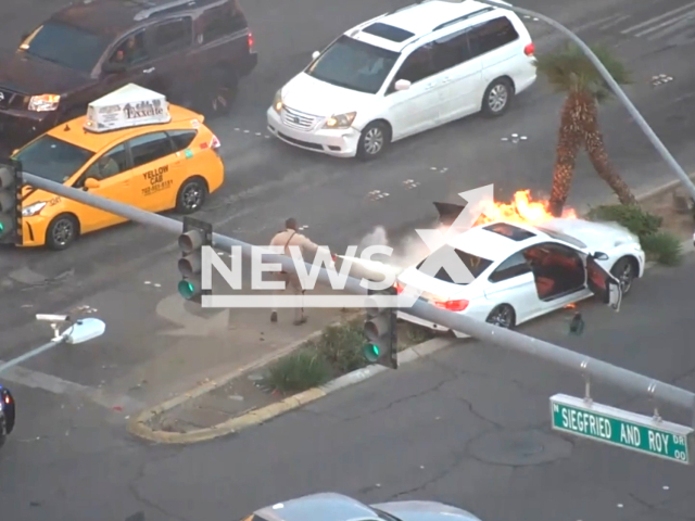 LVMPD Convention Center Area Command officer extinguishes the fire on a burning car, near Las Vegas Boulevard, on On Friday, Jan. 27, 2023. The officer and a bystander pulled a driver from the burning car. Note: Picture is screenshot from a video. (@LasVegasMetropolitanPolice/Newsflash)