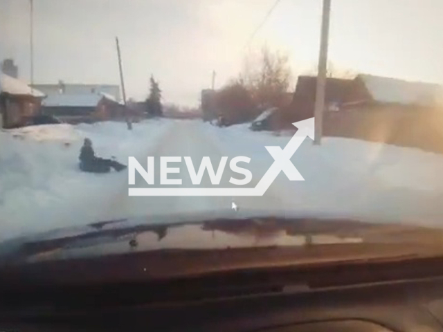 A girl, 9, slides down the snowy hill in front of the car in Yurgamysh, Russia on Sunday, Feb. 5, 2023. The girl was injured and hospitalized. Note: Picture is a screenshot from a video (@gibdd45/Newsflash)