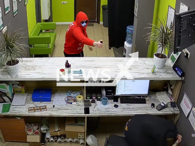 Robber pepper sprays an employee in Noginsk, in Moscow Oblast, Russia, in undated footage. A cash box containing about 140,000 rubles was also stolen. Note: Picture is a screenshot from a video (@mvd50/Newsflash)