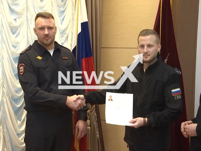 French journalist Adrian Boke, 33, (middle) shakes hands with Russian police officer and holds application for asylum in Moscow, Russia in January, 2023. Putin granted Russian citizenship to the journalist. Note: Picture is a screenshot from a video (@mediamvd/Newsflash)