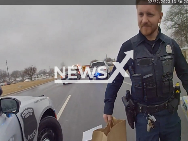 Picture shows a police officer carrying the DoorDash delivery  in Detroit, Michigan, USA, on Wednesday, Feb. 22, 2023. Police officer finished a DoorDash delivery for pregnant driver after car wreck.  Note: Picture is a screenshot from a video. (@SterlingHeightsPolice/Newsflash)