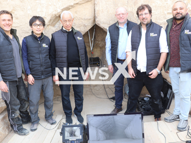 Image shows a part of the research group directly in front of the discovery site, undated photo. Standing from left to right are Johannes Rupfle (TUM), Prof Kunhiro Morishima (Nagoya University, Japan), Prof Hany Helal (Cairo University, Egypt), Prof Christian Grosse (TUM), Prof Jean-Baptiste Mouret (Inria, France), Prof Mohamed Elkarmoty (Cairo University, Egypt). Note: Licensed content. (Scan Pyramids/Newsflash)