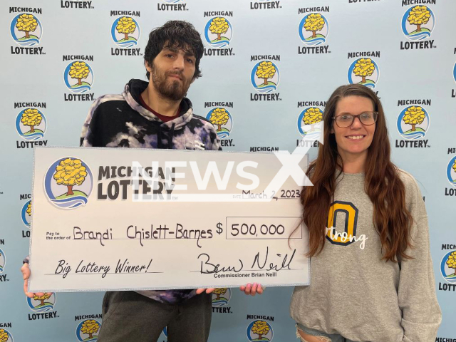 Brandi Chislett-Barnes, 35, and her husband  pose with her lottery wining check, undated. She started screaming and crying when she won USD 500 thousand. 
Note: Licensed photo.  (Michigan Lottery/Newsflash)