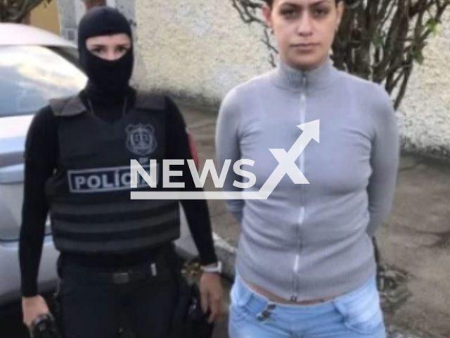 Suliane Abitabile Arantes, 34, known as Elektra poses with police officer in undated photo.     She is considered  one of the most dangerous criminals in Brazil, and recruits for a criminal organization, she was arrested in Sao Paulo, Brazil, on Friday, March, 3, 2023. Note: Police photo. (Policia Civil do DF/Newsflash)