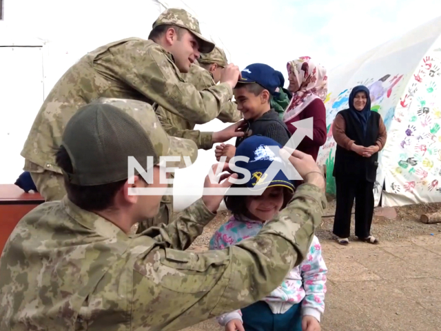 Soldiers give caps to little children, victims of the earthquake, in Turkey, in undated footage. Thousands of people have been left injured and homeless as a result of the earthquake. Note: Picture is a screenshot from a video. (@TCMilliSavunmaBakanligi/Newsflash)