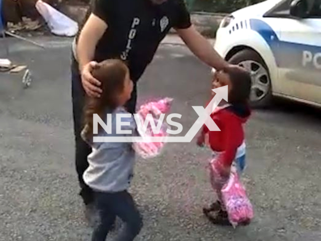 Police officers give gifts to little children, victims of the earthquake, in Hatay, Turkey, in undated footage. Thousands of people have been left injured as a result of the earthquake. Note: Picture is a screenshot from the video. (@EmniyetGM/Newsflash)