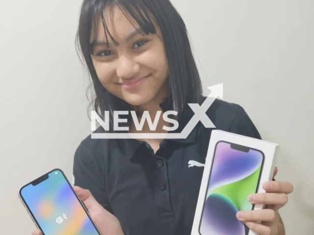 Photo shows Bianca Jemi Wariyava with her new iPhone 14 in Dubai, UAE, undated. She bought it by selling homemade bread in school. Note: Photos were sent to us by Gemini Wariyava Bianca's mother. (Gemini Wariyava/Newsflash)