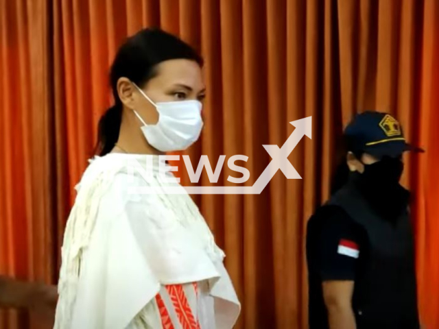 Picture shows Russian tourist Luiza Kosykh, with Bali police officers,  undated.
She was deported after posing naked on a 700-year-old sacred tree in Tabanan, Bali. 

 
 Note: Photo is a screenshot from a video. (Newsflash)