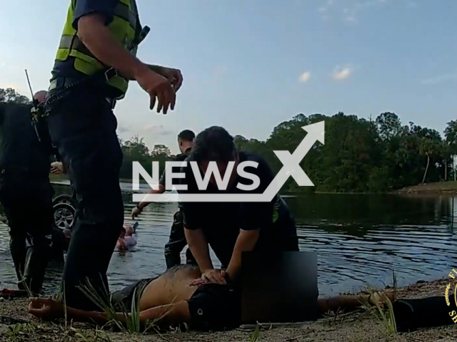 Deputies, firefighters, and civilians give CPR to a driver who was rescued from a submerged car, in Flagler County, Florida, on Sunday, April 16, 2023. The car had crashed into a retention pond at the exit ramp for I-95 and Palm Coast Parkway. Note: Picture is screenshot from a video. (@FLAGLERCOUNTYSO/Newsflash)