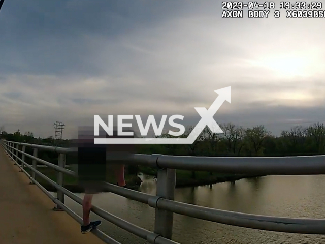 Person attempts to jump from the Kansas River bridge, in Lawrence, Kansas, on Tuesday, April 18, 2023. Police officers successfully deescalated the situation and helped the person. Note: Picture is screenshot from a video. (Lawrence Kansas Police Department/Newsflash)