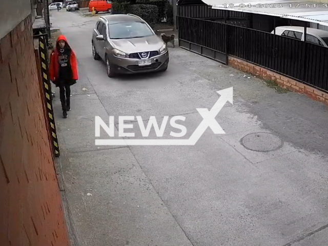 A girl walks down the street as two robbers in a car drive towards her in Angol, Chile, on Tuesday, April 18, 2023.   A dog thwarted the robbery attempt by barking at the attackers. Note: Private photo.  (Newsflash)