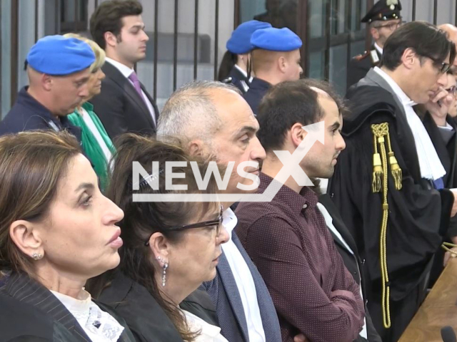 Picture shows  Elona Kalesha, 36, (second from the right), the defence team (right) and the prosecution (left) during the sentencing,   in Florence , Italy, in May, 2023.  She was on trial for the murders of Shpetim Pasho, 54, and Teuta Pasho, 52, and was convicted to 30 years in jail. Note: Photo is a screenshot from a video. (Newsflash)