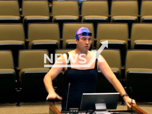 Alex Stein, of Dallas, Texas, attends City Council meeting in women’s swimsuit, holding up a photograph of transgender swimmer Lia Thomas. Note: Picture is a screenshot from a video (Plano/Newsflash)