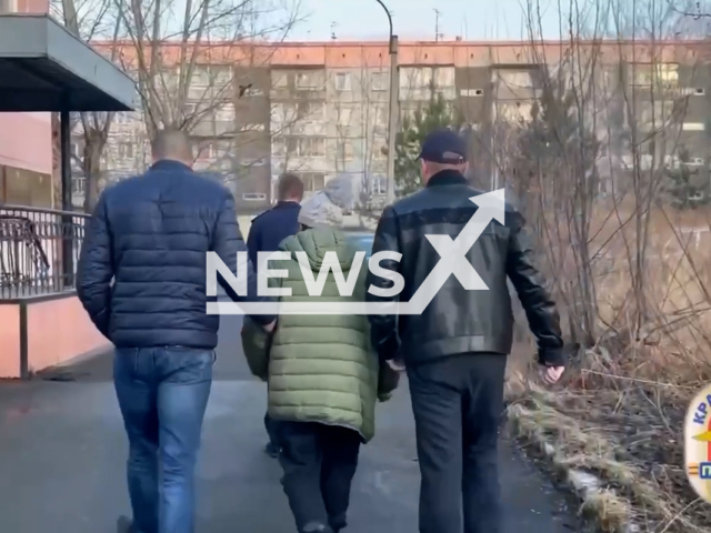 Police officers escort detained unnamed woman, 67, to police department in Krasnoyarsk, Russia on Thursday, May 4, 2023. She is suspected of hiring a killer for her daughter, 48, and her son, 45, over inheritance. Note: Picture is screenshot from a video. (@mvd_24/Newsflash)