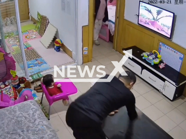 Father pretends he is busy wiping the coffee table when he hears his angry wife shouting in Weifang, China, on 21st March 2022. Note: Picture is a screenshot from a video (897000781/AsiaWire)